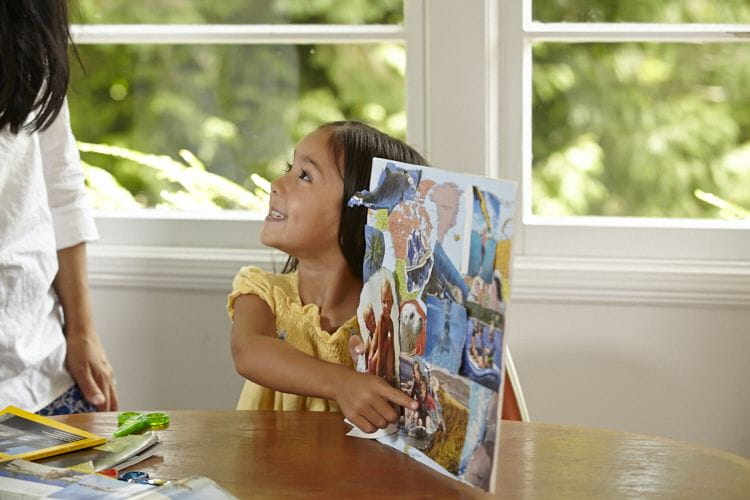 little girl proudly showing her collage to mom